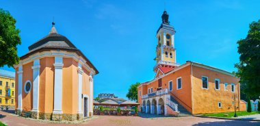 Ermeni kuyusunun parlak turuncu binaları ve Polonya Pazar Meydanı, Kamianet-Podilskyi, Ukrayna 'ya hakim olan uzun ince saat kuleli eski belediye binası.