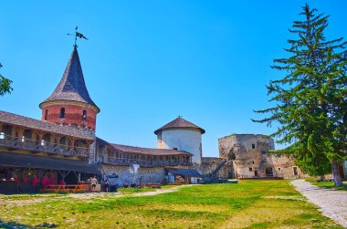 Tarihi Kamianet-Podilskyi Kalesi 'nin avlusu surlarda ahşap galeri, konik çatı kuleleri ve Ukrayna' da açık mutfağı olan küçük bir taverna.