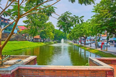 Bereketli gölgeli park Eski Şehir Hendeği boyunca uzanır ve ortaçağ kale duvarı Chiang Mai, Tayland 'ın fıskiyeleri ve harabeleri üzerindeki manzarayı açar.