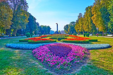 Süslü renkli çiçek yatakları Hull Park 'ın yeşil çimlerinin arasında arka planda tarihi Poltava Savaşı Anıtı manzaralı, Yuvarlak Meydan, Poltava, Ukrayna