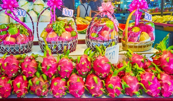The counter of the fresh fruit stall with heap of bright pink dragon fruits and the fruit baskets for gift, Tanin Market, Chaing Mai, Thailand