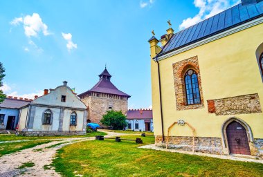Medzhybizh Şatosu 'nun avlusunda farklı amaçlara sahip ortaçağ binaları arasında hoş bir yürüyüş, Ukrayna