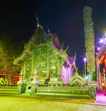 Parlak akşam ışıkları Gümüş Tapınak 'ın (Wat Sri Suphan) ve yanındaki Budist sütunu, Chiang Mai, Tayland' ı süslemektedir.