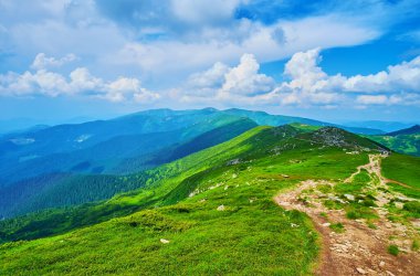 Chornohora Dağı 'nın parlak yeşil yamaçları ve zirveleri mavi gökyüzüne karşı güzel beyaz bulutlarla, Karpatlar, Ukrayna