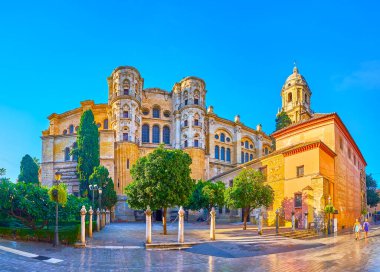 Enkarnasyon Katedrali 'nin giriş kapısı önünde küçük yeşil bir bahçe ve sağdan Malaga, İspanya' dan Santa Maria del Sagrario kilisesi.