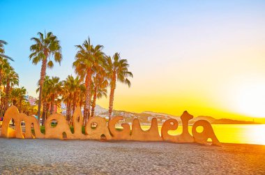 MALAGA, İspanya - 29 Eylül 2019 Malagueta plaj tabelası, palmiyeler ve Akdeniz kıyıları 29 Eylül 'de Malaga' da gün doğumunun parlak ışıklarıyla