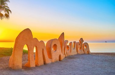 MALAGA, İspanya - 29 Eylül 2019: Malagueta plaj tabelası, 29 Eylül 'de Malaga' da Akdeniz yüzeyine yansıyan parlak ve renkli sabah gökyüzüne karşıdır.