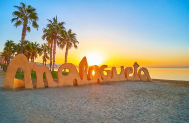 Malaga, İspanya - 28 Eylül 2019: Parlak şafak güneşi, Malagueta sahilindeki uzun palmiye ağaçları ve altın deniz yüzeyiyle birlikte 28 Eylül 'de Malaga' da parlar.