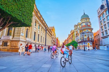 SEVILLE, SPAIN - 29 Eylül 2019: Kalabalık Anayasa Bulvarı 'nda yürüyün ve 29 Eylül' de Seville 'de İspanya Bankası ve bisiklet süren ikonik Edificio la Adriatica binasını izleyin.