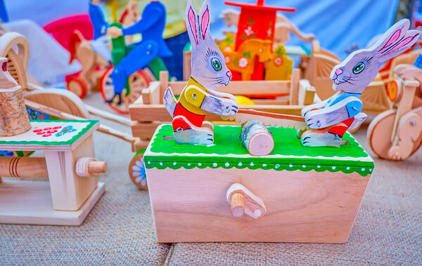 The wooden moving painted toy in form of rabbits sawing firewood on carpenter's stall on Independence Day Fair in Dnipro, Ukraine