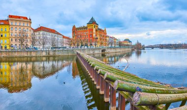 Arka planda Smetana Embankment, Prag, Çek Cumhuriyeti 'nde tahta buzkıran ve kırmızı Bellevue konağı ile ayna Vltava Nehri yüzeyi manzarası