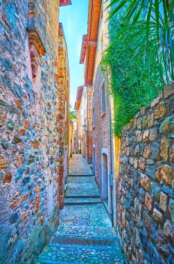 Her iki tarafında yüksek duvarlar olan küçük taş sokak, Morcote, İsviçre.