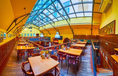 PRAG, CZECH REPUBLIC - 5 Mart 2022: Prag 'da geleneksel U Vejvody pub-restoranının ahşap mobilya ve cam tavanı