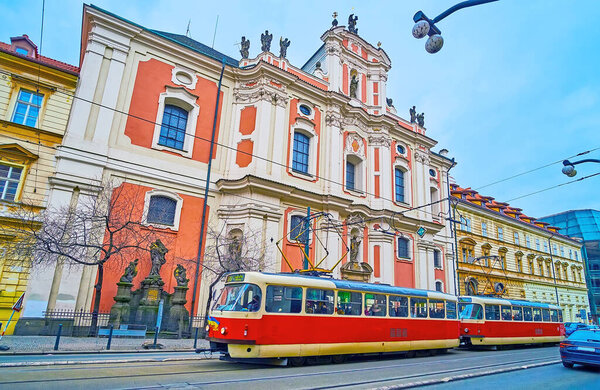 The bright red vintage tram, riding down the Narodni Avenue in front of St Ursula Church, Prague, Czech Republic