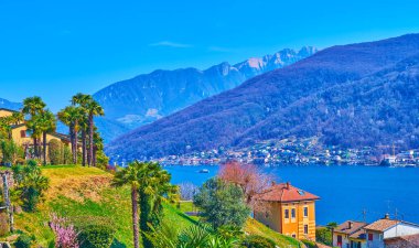 Güzel bir palmiye bahçesi, sulu çimenler, küçük evler ve Lugano Gölü, Morcote, İsviçre manzarasının tadını çıkar.