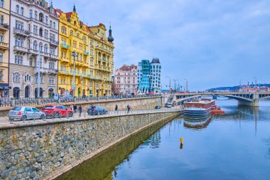 PRAG, CZECH REPUBLIC - 5 Mart 2022: Masaryk Embankment ve Vltava Nehri 'nin arkasındaki Masaryk Dekonstrüktivist tarzı Dans Evi üzerine renkli tarihi yapılar, 5 Mart' ta Prag 'da