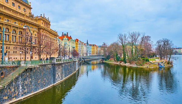 The tall trees of park on Slavonic Island, located on Vltava River and connected with Masaryk Ebankment by the small bridge, Prague, Czech Republic