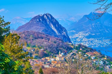 Parco San Grato 'nun bakış açısı, arka planda görülen eski Carona, Monte San Salvatore, Lugano Gölü, Monte Bre ve Monte Boglia' nın kırmızı kiremit çatılarını gözler önüne seriyor.