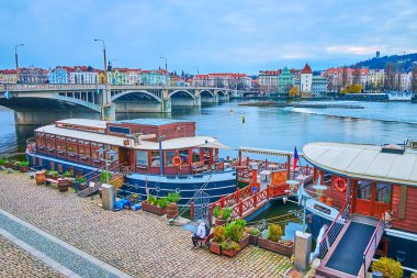 Çek Cumhuriyeti 'nin Prag kentinde bulunan oposite bankasındaki Jirasek Köprüsü ve Smichov semti manzaralı Vltava Nehri kıyısındaki klasik tekne otelleri ve restoranlar