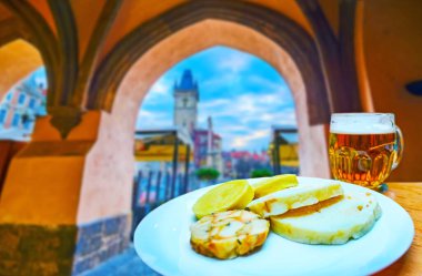 Enjoy the dinner on Old Town Square, traditional knodel boiled dumplings and lager beer with a view on Old Town Hall clocktower through the arch, Prague, Czech Republic