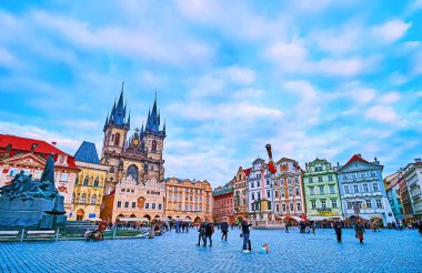 PRAGUE, CZECH REPUBLIC - 5 Mart 2022: Jan Hus Memorial ve Tynsky Church Belfries ile Eski Şehir Meydanı üzerinde parlayan alacakaranlık gökyüzü Prag 'daki ortaçağ evlerinin arkasında, 5 Mart' ta