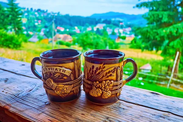 Kırsal dağ arka planında sıcak Karpatya bitkisel çayıyla el yapımı iki güzel kupa Vorokhta, Ukrayna