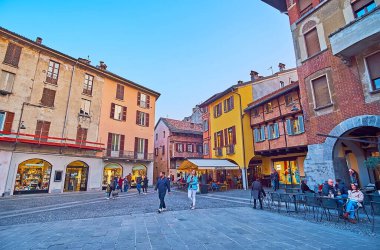 COMO, ITALY - 20 Mart 2022: Piazza del Mercato del Grano (Tahıl Pazarı Meydanı) 20 Mart 'ta Como' da tuğla cepheli, eğimli duvarlı, çökmüş alçı ve açık hava restoranlarında tarihi konutlar