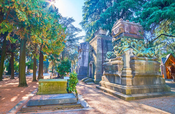 The shady alley among picturesque funeral shrines and tombs, Monumental Cemetery in Milan, Italy