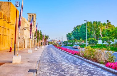 Al Seef caddesi, klasik kerpiç evleri, renkli çiçek yatakları ve yolun arkasındaki yemyeşil ağaçlar, Dubai, BAE