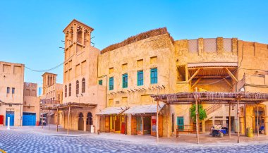 Al Seef, Dubai, BAE 'de yer alan rüzgar yakalayıcıları ve turist dükkanları olan manzaralı klasik kerpiç evlerinin panoraması