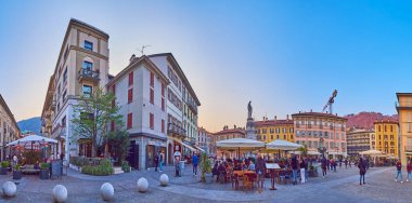 COMO, ITALY - 20 Mart 2022: 20 Mart 'ta Como' da kalabalık yayalar Alessandro Volta Meydanı 'nda açık hava restoranları ve barlarıyla günbatımı manzarası