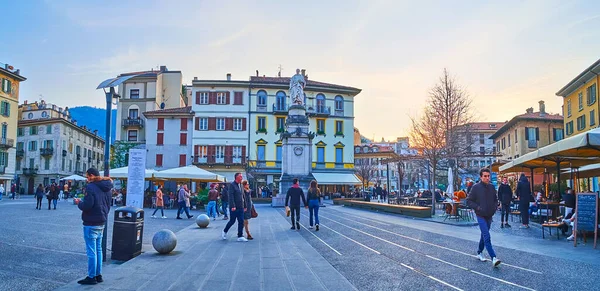 COMO, İtalya - 20 Mart 2022: Alessandro Volta Meydanı akşam panoraması Volta anıtı manzaralı eski binalar ve restoranların teraslarına karşı, 20 Mart 'ta Como' da