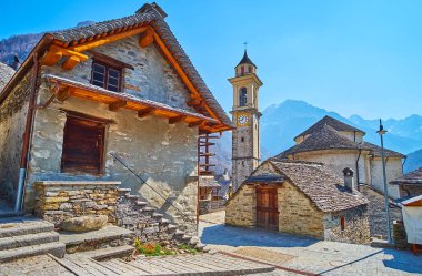 Santa Maria Lauretana Kilisesi 'nin çan kulesi ve taş kubbeleri Sonogno, Valle Verzasca, İsviçre' nin yaşayan taş evlerinin arkasında görülmektedir.