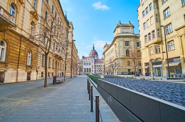 Pedestrian Alkotmany Street, lined with historic edifices, with Trianon Memorial amid the walkway and with Parliament building in background, Budapest, Hungary
