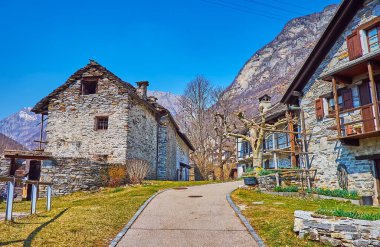 Frasco 'nun arka planında eski taş evler ve dağlar olan küçük caddesi, Valle Verzasca, İsviçre