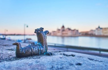 BUDAPEST, HUNGARY - 27 Şubat 2022: Budapeşte 'de 27 Şubat' ta Tuna Nehri ve Parlamento silüetine karşı Kolodko 'nun küçük bronz Fokukac heykeli