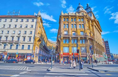 BUDAPEST, HUNGARY - 27 Şubat 2022: Eklektik Stil Anker Sarayı 'nın yan duvarlı geniş Bajcsy-Zsilinszky Caddesi, dar kıvrımlı Anker Koz sokağı ve birçok mağaza, 27 Şubat' ta Budapeşte 'de