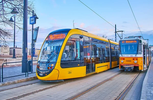 BUDAPEST, HUNGARY - 27 Şubat 2022: Batthyany Ter tramvay durağı iki sarı tramvaylı - modern ve klasik, 27 Şubat 'ta Budapeşte' de