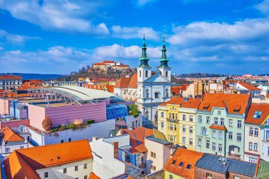 Kırmızı kiremitli çatıları olan eski Brno kasabası, St Michael Kilisesi kuleleri, alışveriş merkezinin modern çatısı ve arka planda Spilberk kalesi, Çek Cumhuriyeti