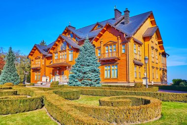 MEZHİHİRYA, UKRAINE - 26 Ekim 2021: Mezhyhirya 'daki ahşap Honka kulüp binasının önündeki yeşil çimen ve süs ağacı çalıları