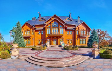 MEZHYHIRYA, UKRAINE - OCT 26, 2021: The facade of wooden Honka club house of Mezhyhirya Residence, surrounded with ornamental park, on Oct 26 in Mezhyhirya