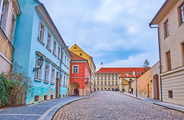 Arka planda Czernin Sarayı, Hradcany, Prag ve Çek Cumhuriyeti 'nin barok duvarları ve kırmızı fayans manzaralı eski renkli evlerle dolu tarihi Loretanska Caddesi' nde yürüyün.