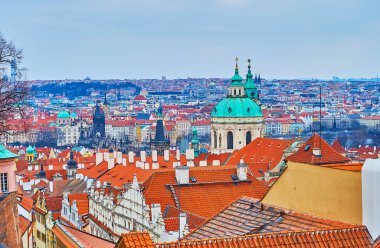 Mala Strana 'nın eski kiremit çatıları (Küçük Mahalle) St. Nicholas Kilisesi' nin yeşil kubbesinin önünde Charles Köprüsü 'nün Gotik kuleleri arka planda, Prag, Çek Cumhuriyeti