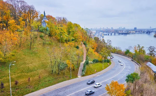 The traffic on Volodymyrsky Descent road, leading to Dnieper River embankment at St Volodymyr Hill, covered with autumn park, Kyiv, Ukraine