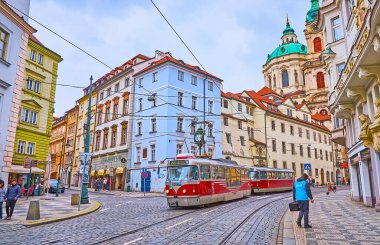 PRAG, CZECH REPUBLIC - 6 Mart 2022: Eski kırmızı tramvayı ve arka planda Aziz Nicholas Kilisesi olan Karmelitska Caddesi, 6 Mart 'ta Prag' da