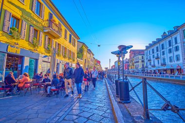 MILAN, ITALY - APRIL 9, 2022: The evening strolls on Naviglio Grande Canal, on April 9 in Milan, Italy