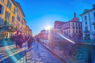 MILAN, ITALY - 9 Nisan 2022: Naviglio Grande Kanalı üzerindeki parlak günbatımı, 9 Nisan 'da Milano' da restoranları, barları ve mağazaları olan renkli evlerle dolu.