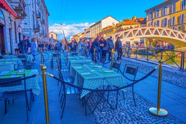 MILAN, ITALY - APRIL 9, 2022: The outdoor restaurants ready for everyday nightlife of Naviglio Grande Canal, on April 9 in Milan, Italy