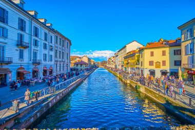 MILAN, ITALY - APRIL 9, 2022: Naviglio Grande Canal reflects the bright blue sky and colorful houses, located on its embankments, Navigli neighborhood, on April 9 in Milan