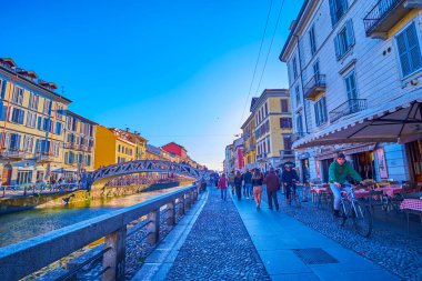 MILAN, ITALY - APRIL 9, 2022: Walk along Naviglio Grande Canal, the popular leisure place among locals, on April 9 in Milan, Italy